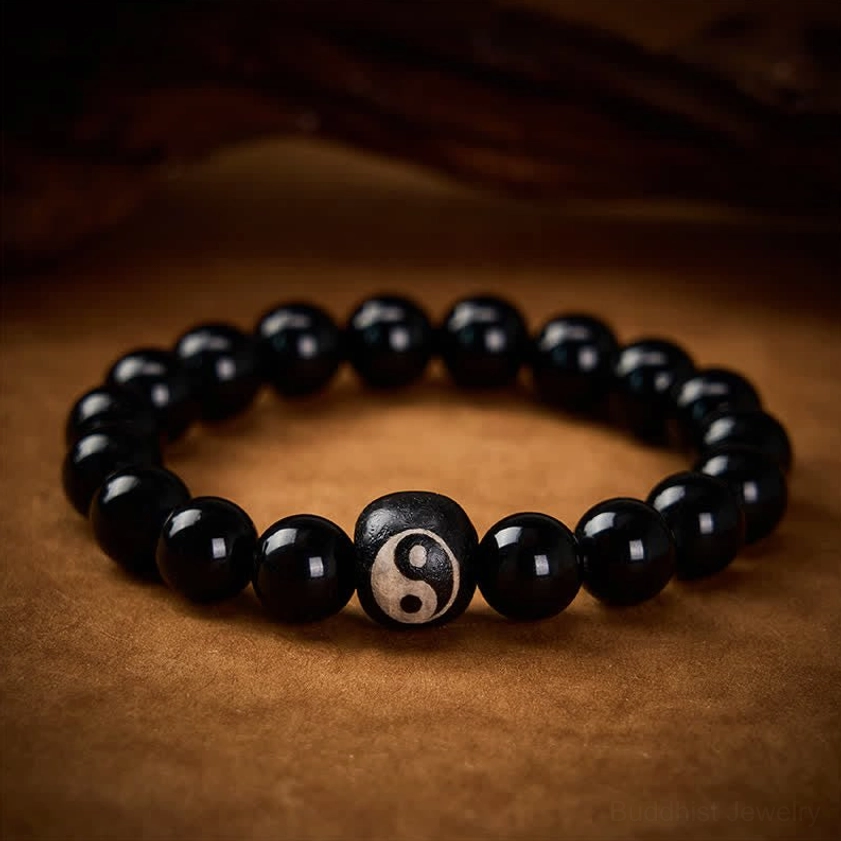 Natural black stone yin yang bracelet with polished beads on dark wooden surface low angle