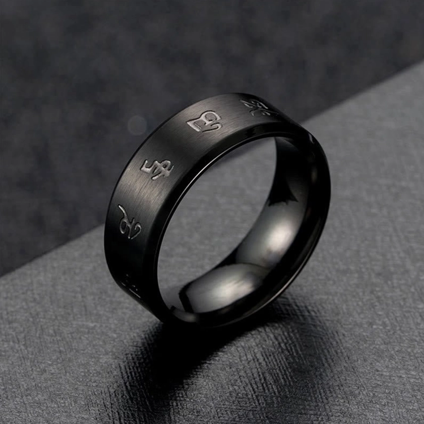 Low-angle side view of black titanium steel Jambhala ring with brushed exterior finish and engraved religious script details