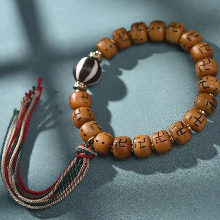 Black and white Dzi bead Buddhist bracelet with camel bone, metal accents, and traditional woven tassel