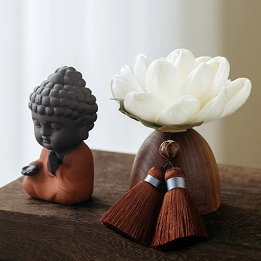 Buddhist Buddha figurine carved from dark wood with reddish-brown robe on lotus stand with tassels