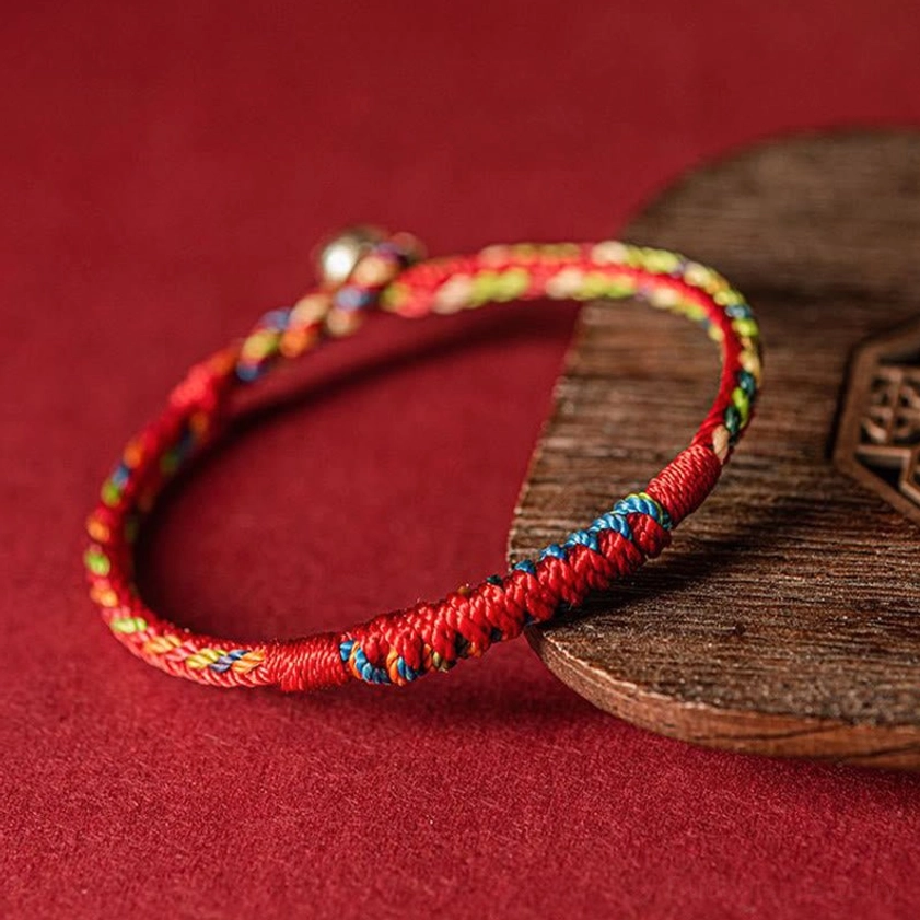 Close-up of handmade Buddhist protection bracelet showing detailed braided texture, mixed color threads, and adjustable clasp