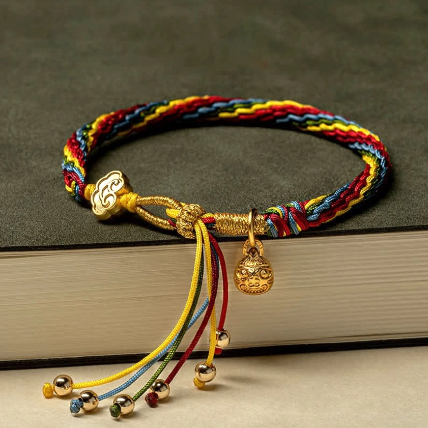 Buddhist blessed string bracelet worn on model wrist with gold accents and protective red cord close-up