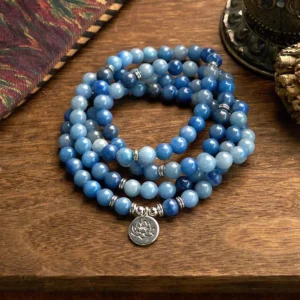 108 blue aventurine mala beads bracelet with silver lotus pendant flat lay on wooden table