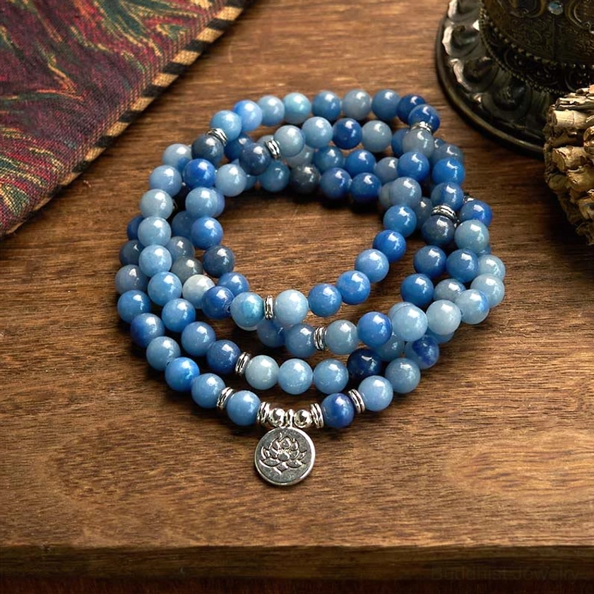 108 blue aventurine mala beads bracelet with silver lotus pendant flat lay on wooden table
