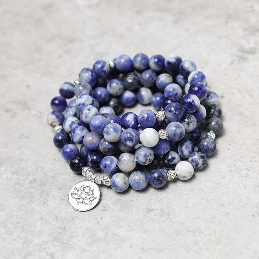 Natural blue aventurine round beads stacked close-up with silver lotus pendant spiritual jewelry