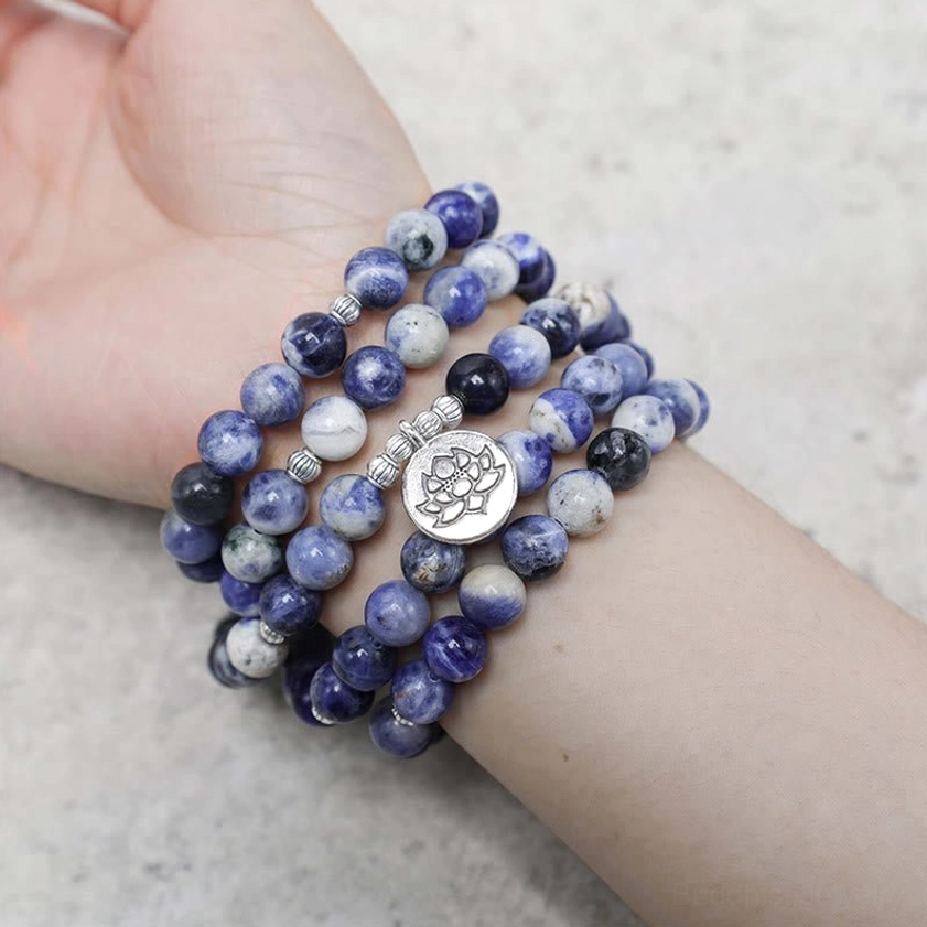 Blue aventurine mala bracelet worn on wrist showing blue-white striped stone beads with lotus charm