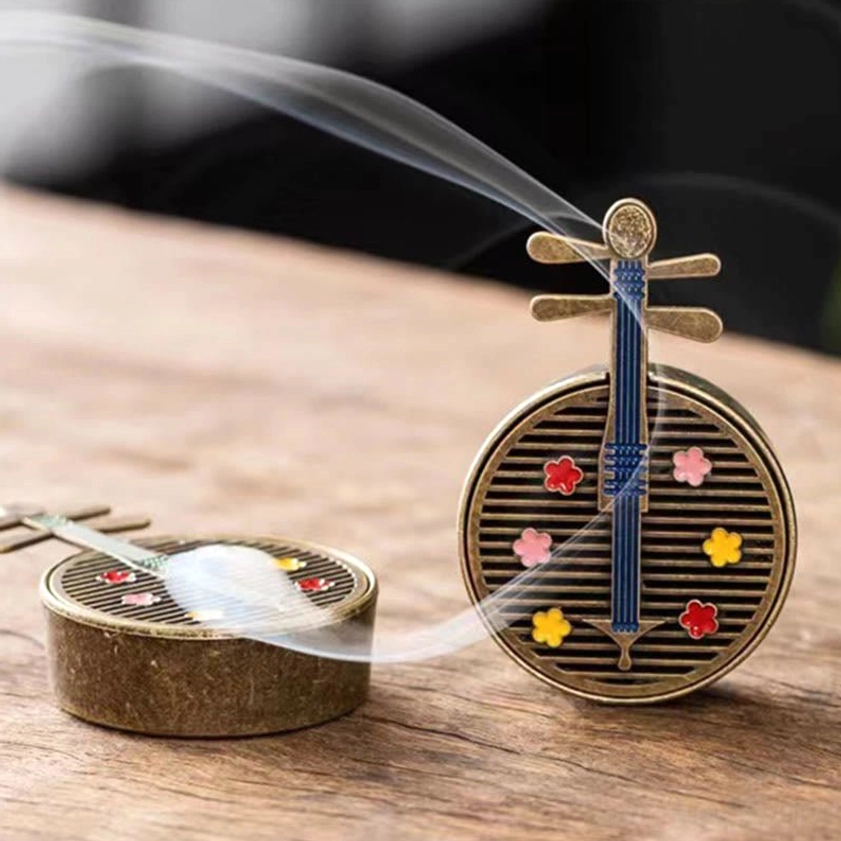 Two blue and bronze pipa incense burners on wooden display with decorative flower decals