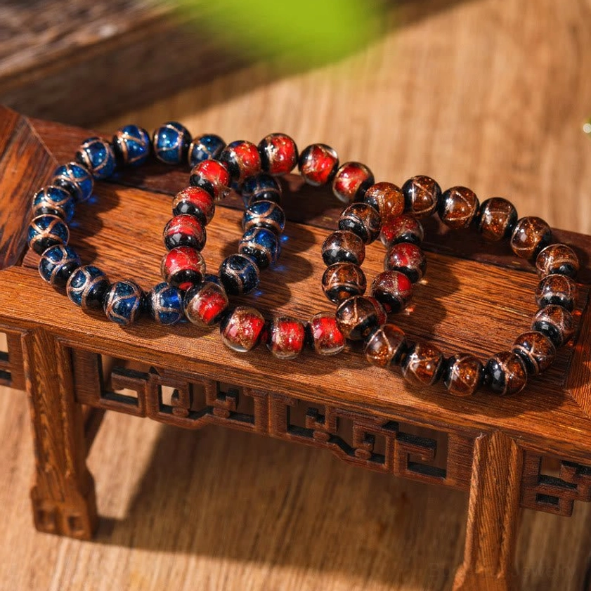 Deep blue and reddish-brown liuli glass Buddhist meditation bracelets on retro wooden tabletop