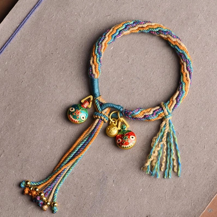 Blue colorful braided Buddhist string bracelet with enamel pendants and tassel on gray paper, flat lay top view