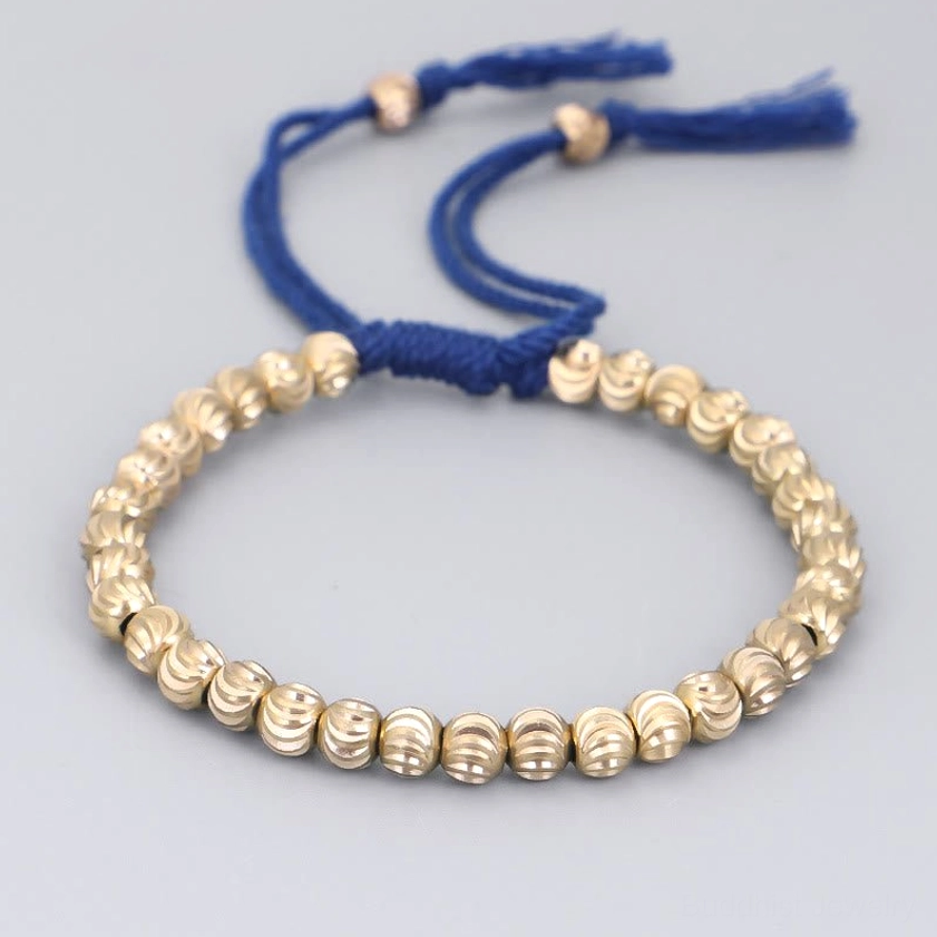 Blue adjustable Buddhist bracelet with copper beads and tassel fastener, top-down product view