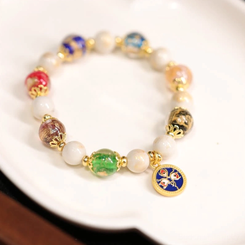 Blue God of Wealth Buddhist bracelet featuring blue face charm, green glass beads, white porcelain beads and gold spacers