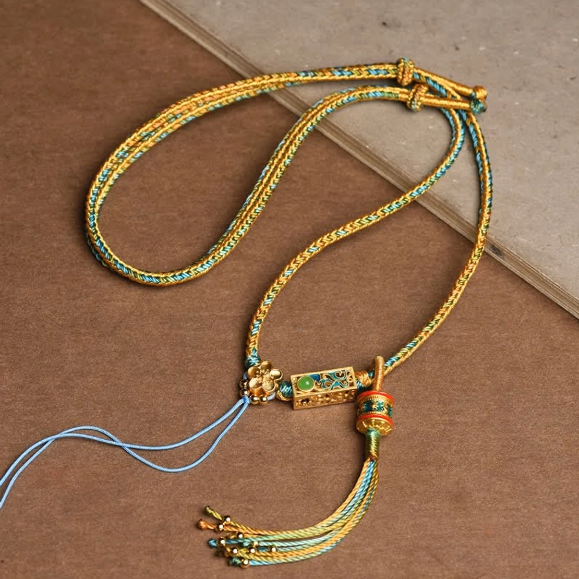 Blue and gold braided copper string Buddhist necklace with blue gradient tassel and gold enamel charm for spiritual balance