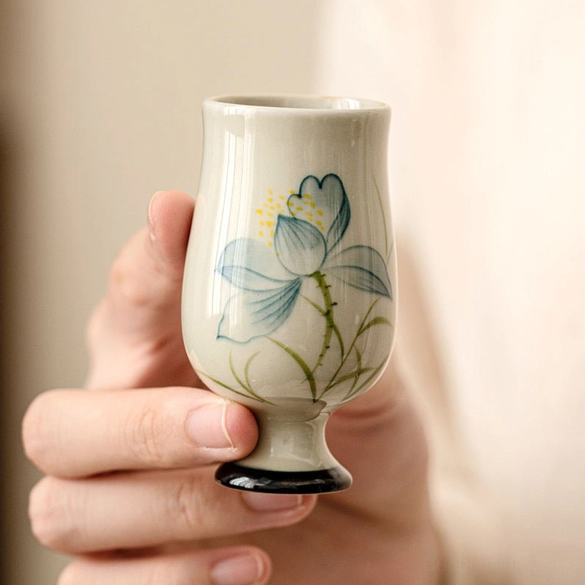 Blue and gold hand-painted lotus design on ceramic tea cup with black base rim - meditation mindfulness vessel