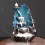 Blue lotus leaf ceramic backflow incense burner front three-quarter view showing teal and dark brown glazed ceramic with flowing smoke effect