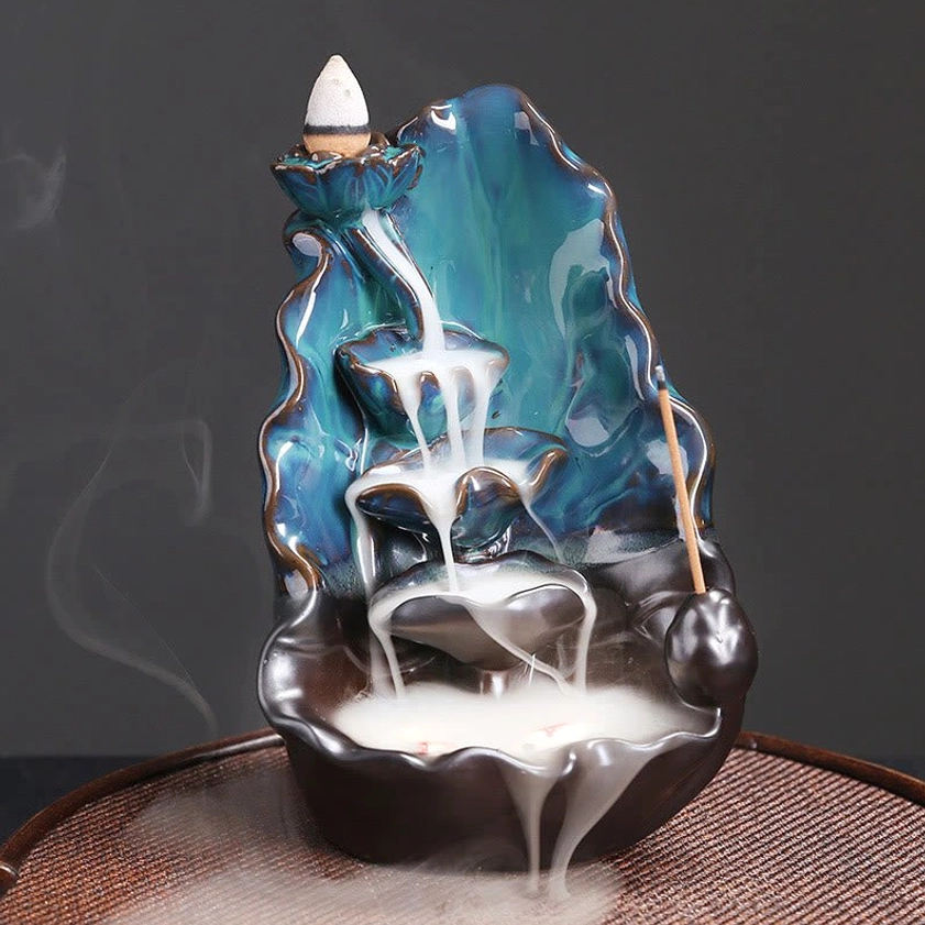Blue lotus leaf ceramic backflow incense burner front three-quarter view showing teal and dark brown glazed ceramic with flowing smoke effect