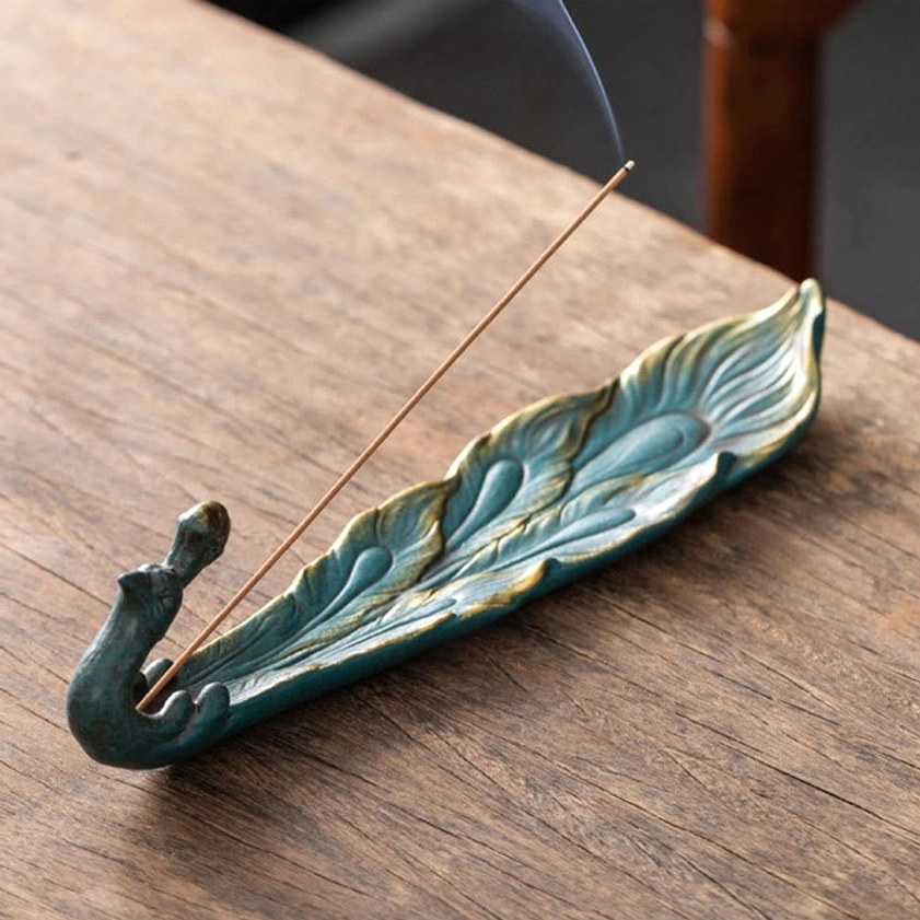 Blue-green peacock incense burner with gilded head feather pattern and burning incense smoke