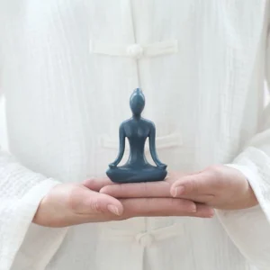 Blue ceramic yoga meditation figurine in lotus pose held in hand - handcrafted Buddhist mindfulness statue for home décor