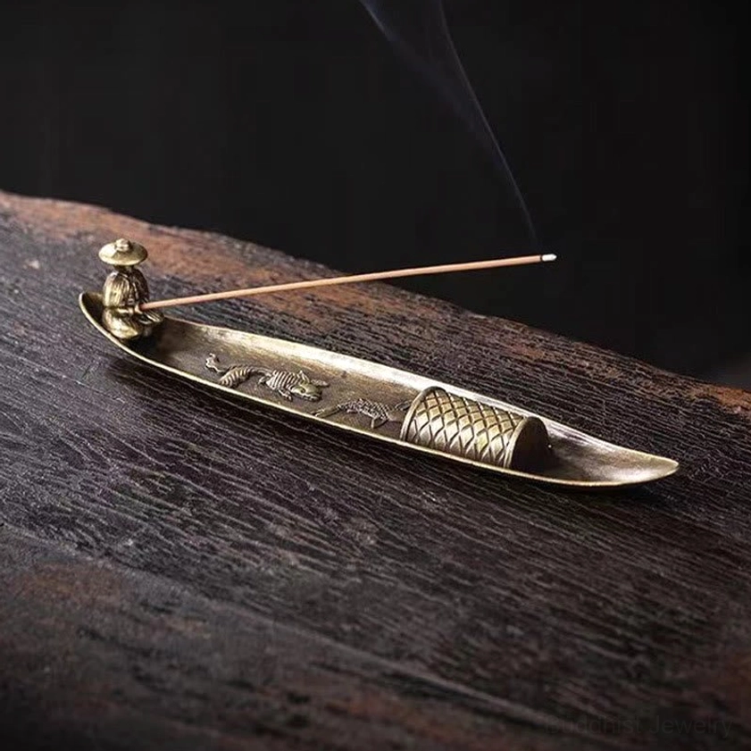 Low side angle view of boat shaped incense burner with smoking incense on dark wooden table