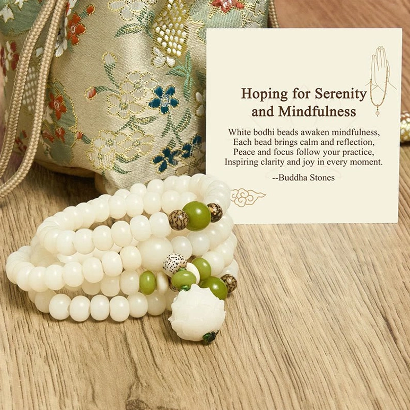 White bodhi prayer beads with floral embroidered drawstring bag and green accent beads, wooden tabletop