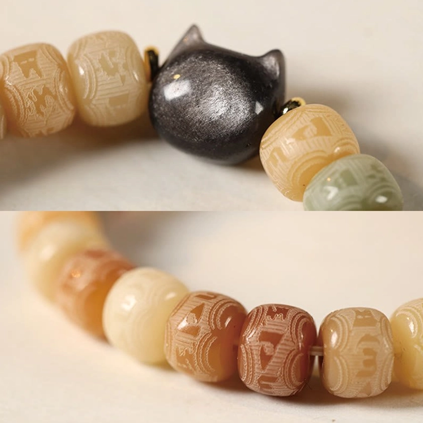 Macro close-up of carved Om Mani Padme Hum mantra beads and silver sheen obsidian cat head charm detail