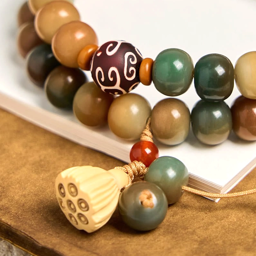 Close-up detail shot of bodhi seed bracelet highlighting carved wooden lotus charm and polished bead texture