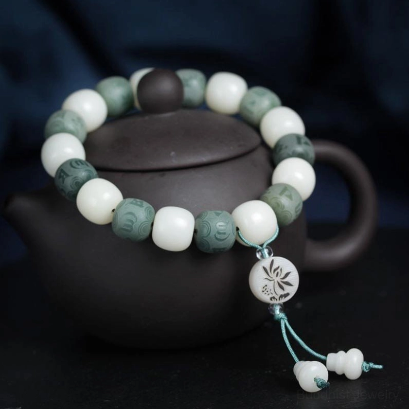 Overhead three-quarter view of white bodhi seed six-word mantra bracelet with organic bead texture and lotus charm