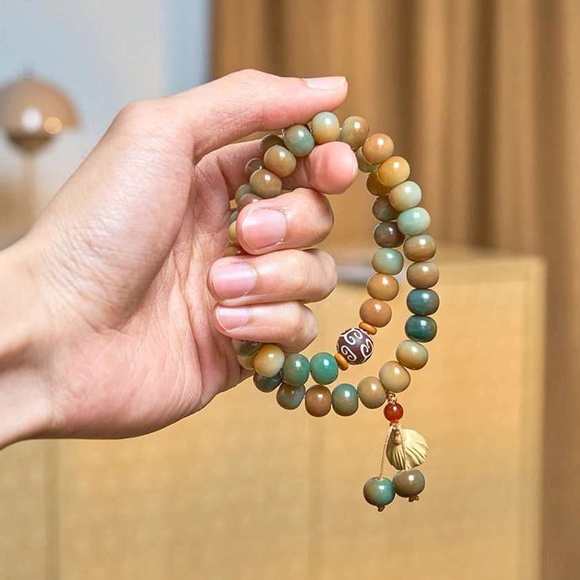 Hand holding flexible bodhi seed Buddhist bracelet displaying bead arrangement and spiritual charm details