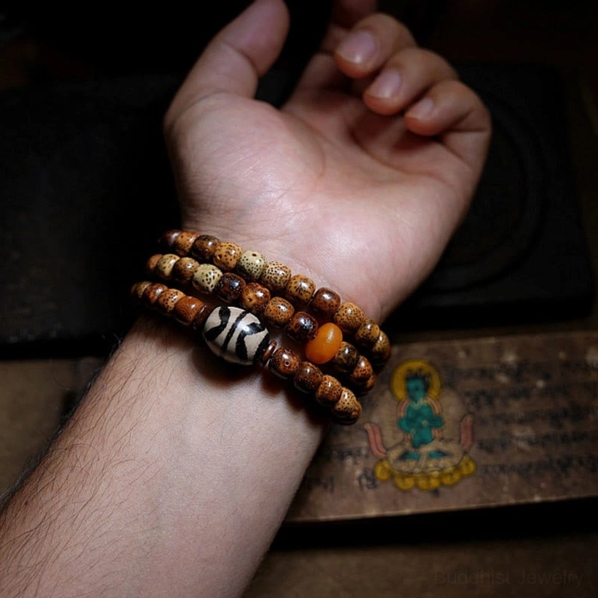 Partial bodhi seed mala with loose amber disc-shaped agate beads arranged on dark background