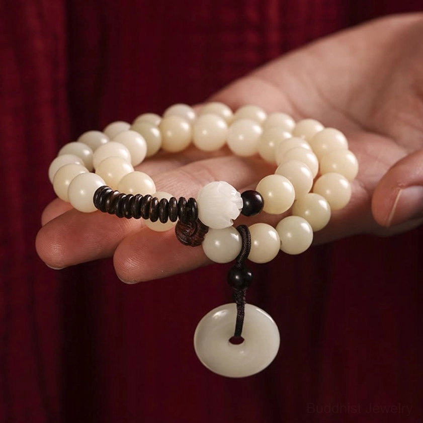 Close-up palm hold view of white and cream bead meditation bracelet with black spacers and peace buckle, worn on hand