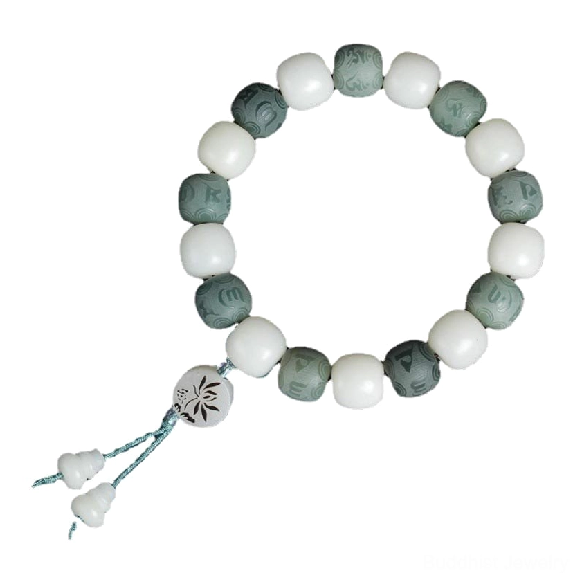 Side flat lay view of white bodhi mantra bracelet with simple tassel and two-tone bead design on plain dark background