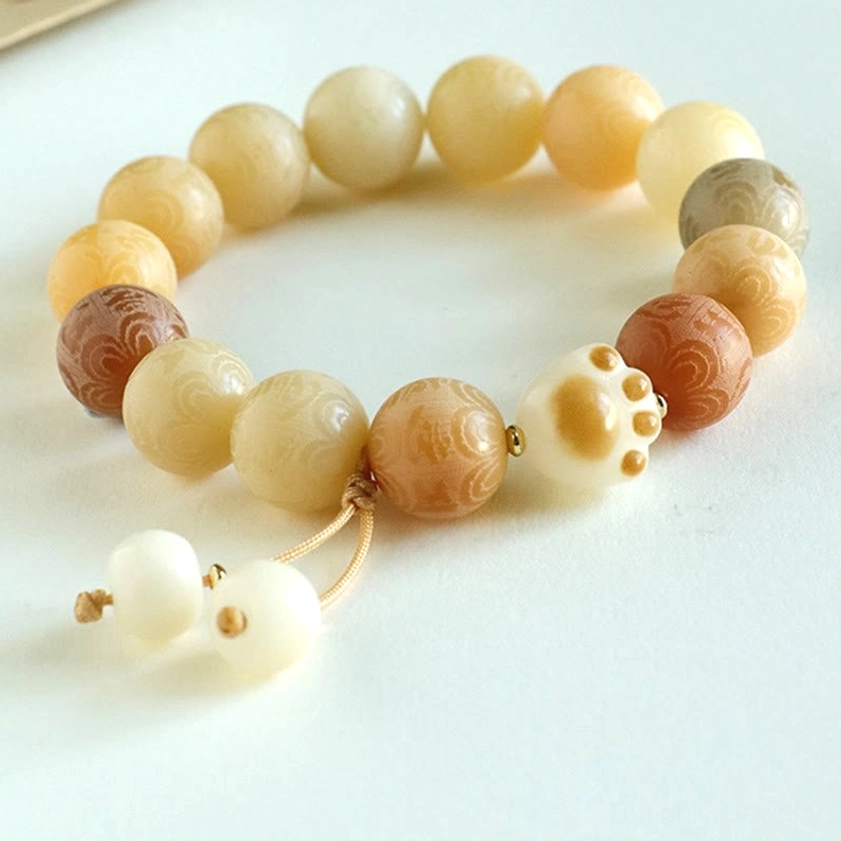 Close-up of tassel charm pendants and copper alloy accents on Bodhi Seed Om Mani Padme Hum bracelet