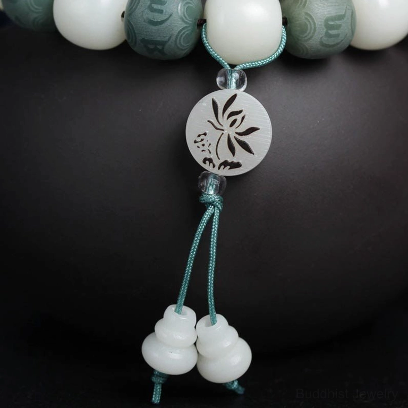 Close-up three-quarter view of bodhi bracelet tassel featuring teal cord, double gourd pendants, and engraved lotus charm