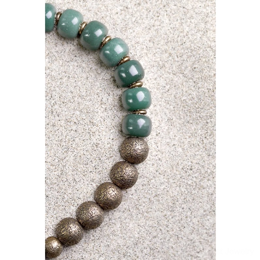 Cyan bodhi seed copper bracelet partial flat lay displaying alternating cyan barrel beads and bronze metal accents