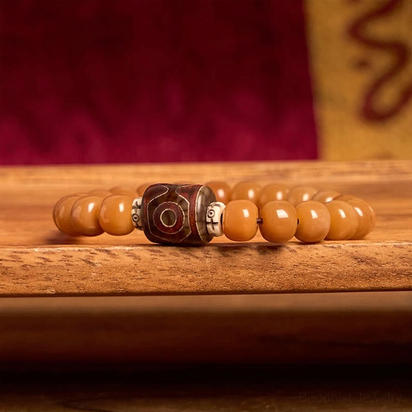 Stacked Bodhi seed beads with central hand-painted Dzi bead and metal accent spacers in flat lay composition on wooden table background