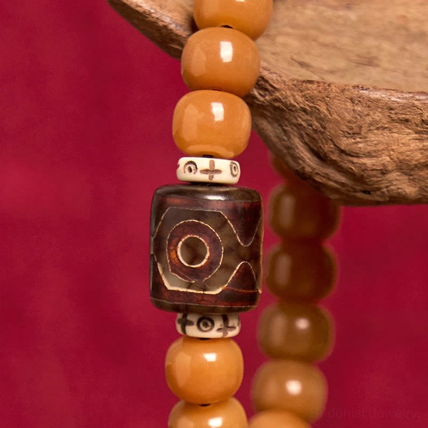Close-up detailed view of Bodhi seed and Dzi bead bracelet showing cross-patterned white metal spacers and intricately hand-painted protective Dzi bead