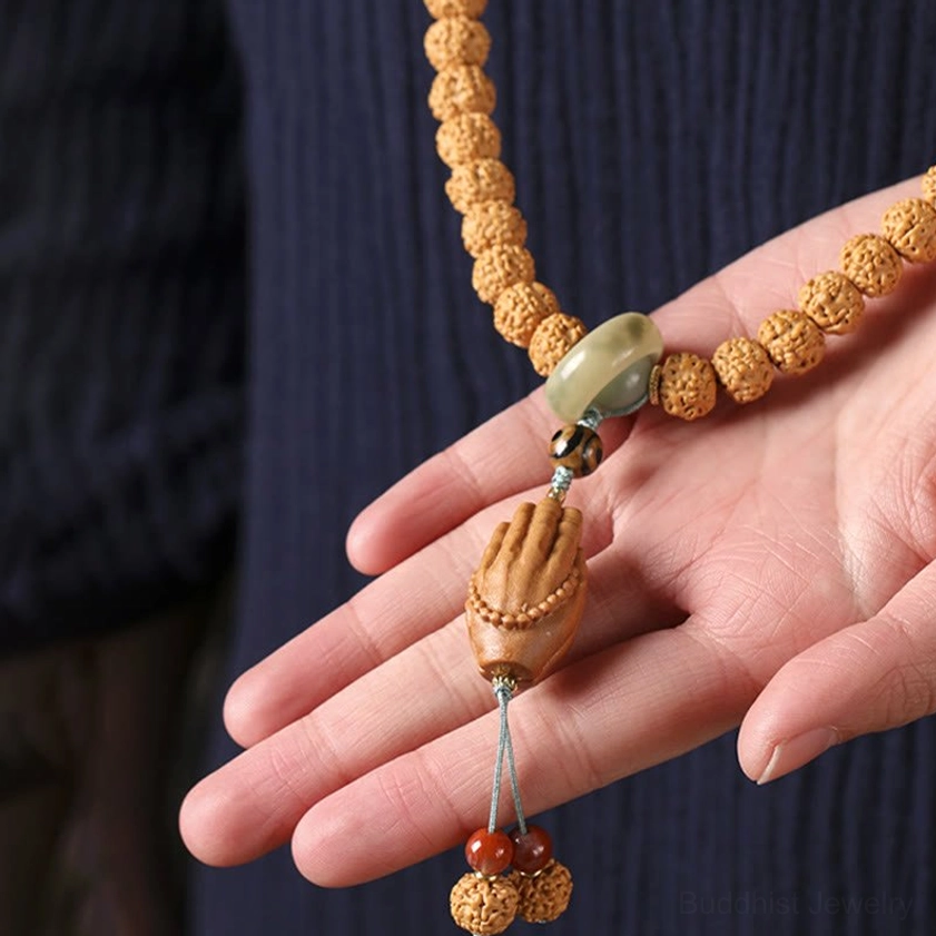 Bodhi seed prayer bracelet with protective Dzi bead held in hand showing Buddha hand pendant detail and bead quality