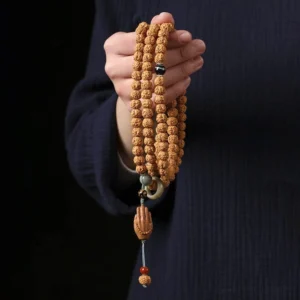 Bodhi seed Buddhist bracelet with three-eye Dzi bead and carved Buddha hand charm held in palm close-up