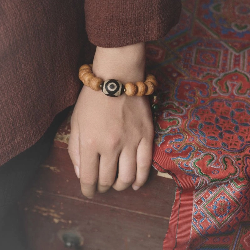 Person wearing bodhi and dzi bead mala bracelet on wrist with vintage styling