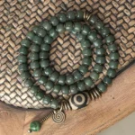 Bodhi seed and hand-painted dzi bead triple wrap bracelet with vintage bronze hardware, top-down flat lay view
