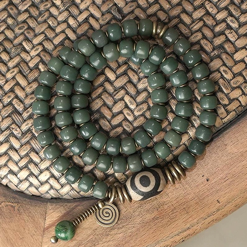 Bodhi seed and hand-painted dzi bead triple wrap bracelet with vintage bronze hardware, top-down flat lay view