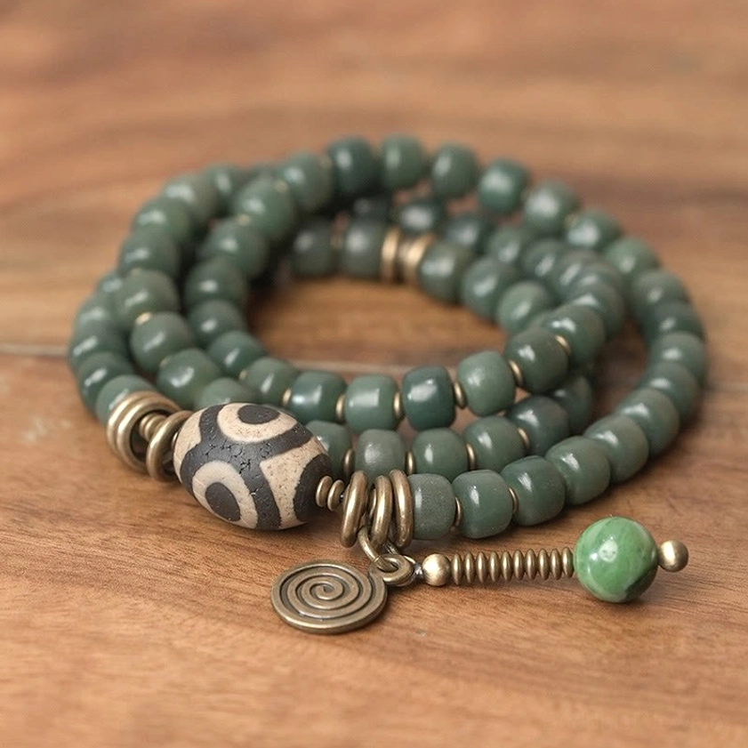 Top-down overhead view of triple wrap dzi bead bracelet showing uniform dark green beads and pendant
