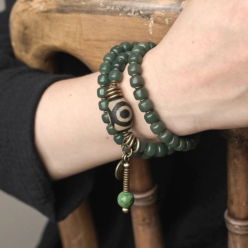 Close-up side view of dzi bead wrap bracelet worn on wrist, showing matte green beads and antique bronze details