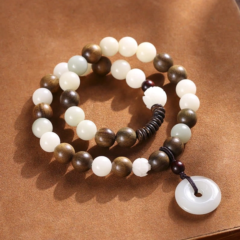 Two-tone wooden beads and peace buckle charm double wrap bracelet on brown suede, showing bead detail and smooth elastic cord