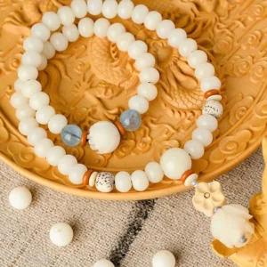 White jade bodhi lotus blessing bracelet with aquamarine beads overhead view on wooden tray