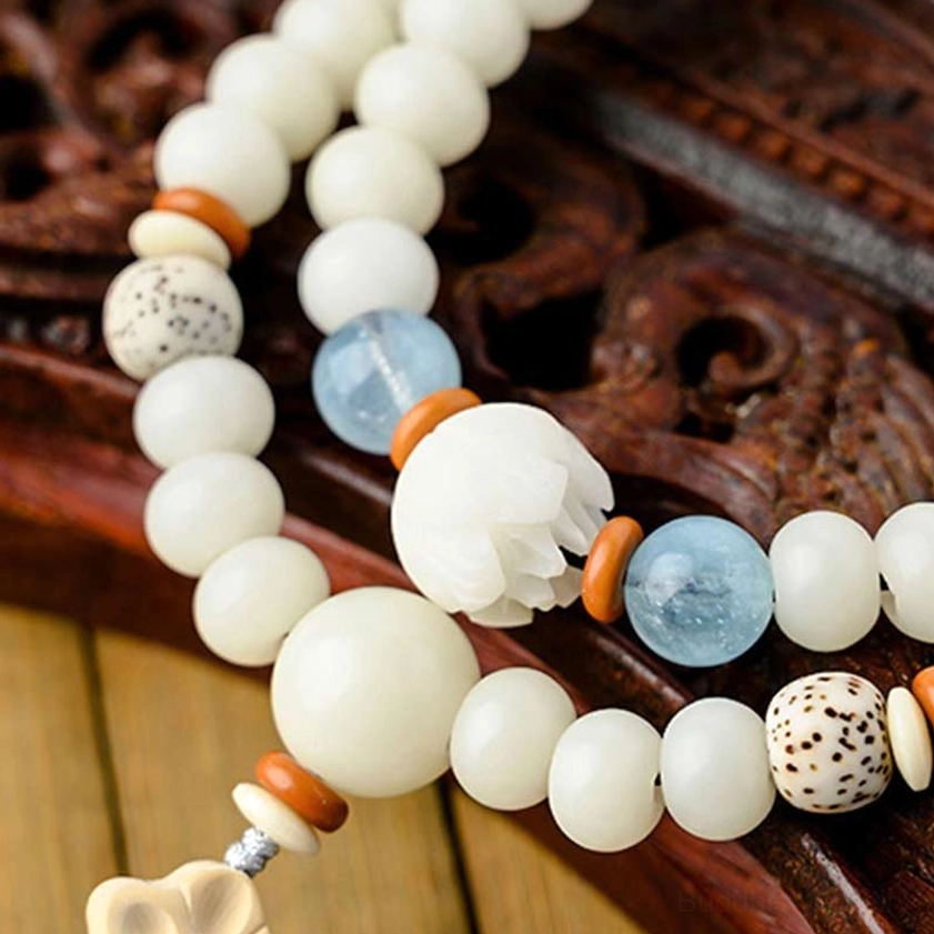 Detailed close-up of bodhi beads with lotus pendant on carved wooden background