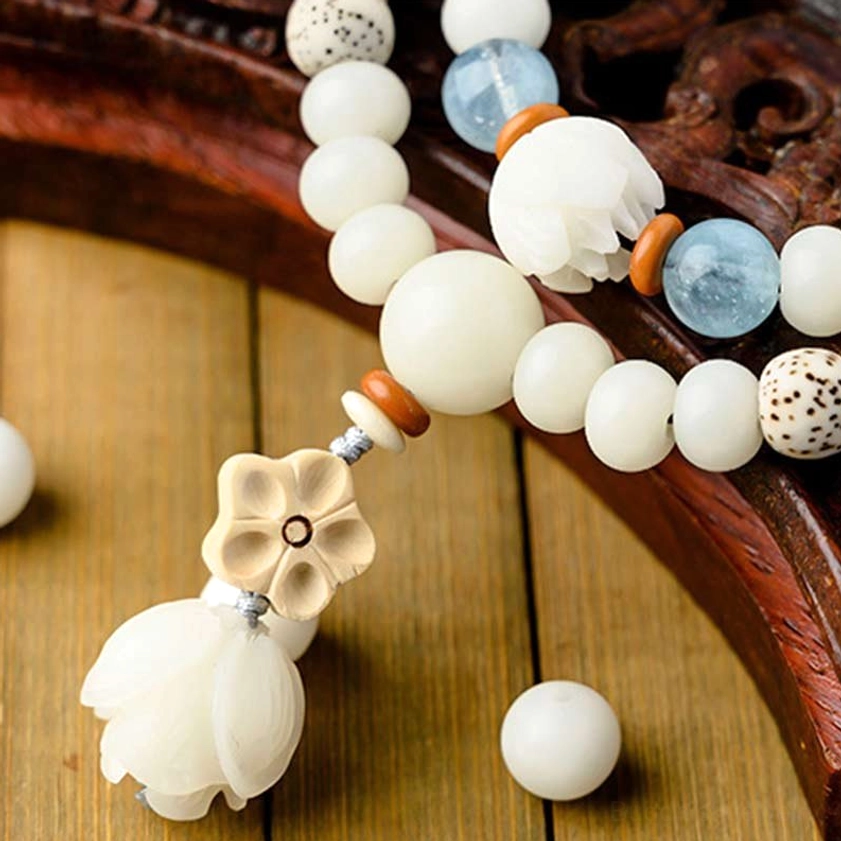 White jade bodhi bracelet with lotus pendant and aquamarine accent beads on wooden surface