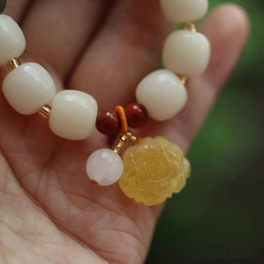 Detailed close-up of bodhi seed bracelet featuring rose charm, red spacer beads, and pink accent bead against neutral background