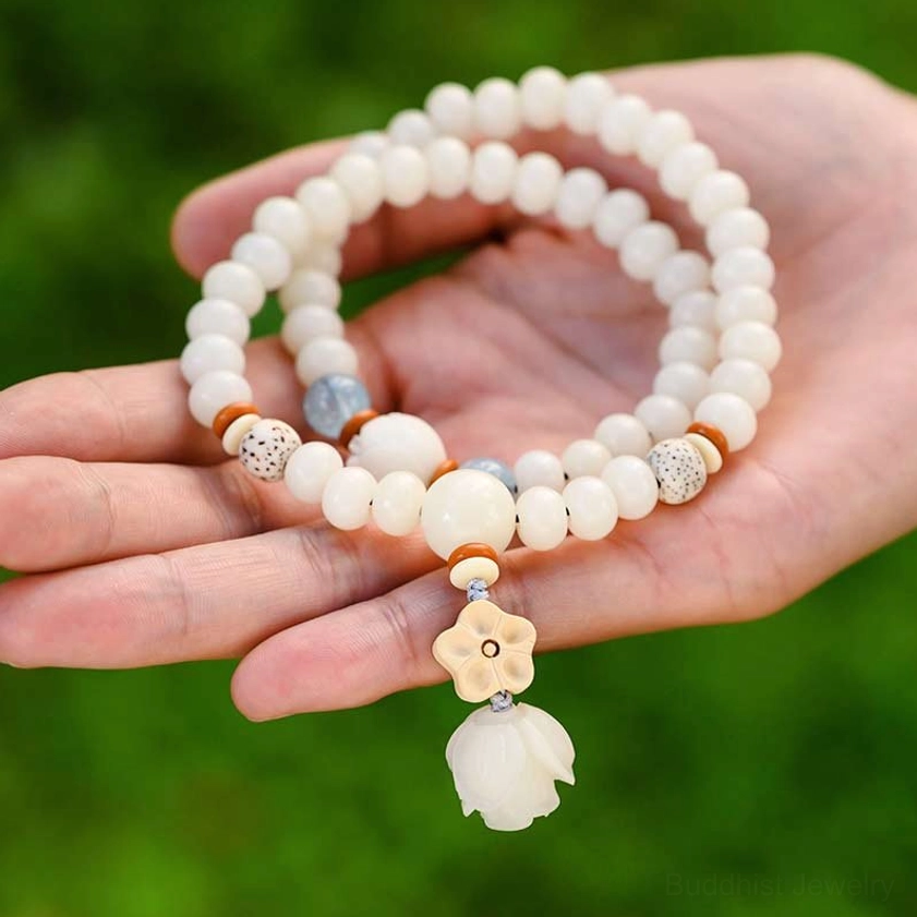 Buddhist bodhi lotus bracelet held in palm against green foliage background