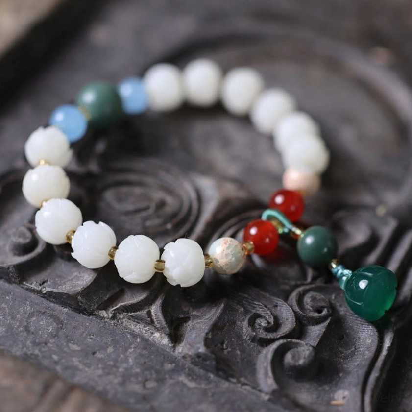 Spiritual bodhi seed lotus bracelet on stone tray featuring white carved lotus beads and jade centerpiece