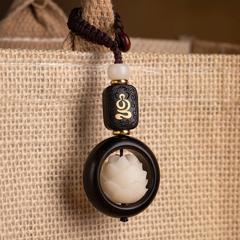 Buddhist spiritual keychain hanging on burlap bag strap demonstrating functional everyday wear and portability